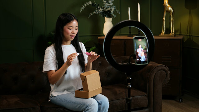 Young Asian woman unboxing and showing a cosmetic product for her online video