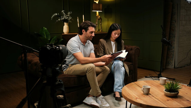 Two people collaborating on a podcast interview, discussing content in a recording studio