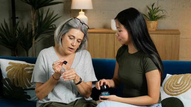 Grandmother and adopted granddaughter sharing a moment while discussing beauty products on a couch