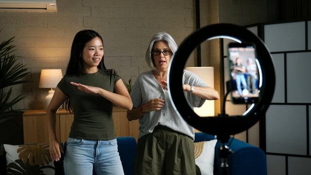 Intergenerational women creating online content together using a smartphone and ring light