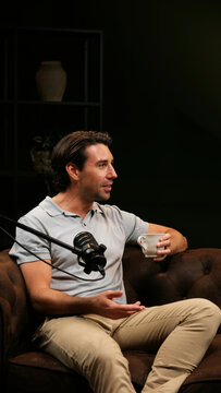 Man speaking into a microphone, recording a podcast, holding a coffee cup