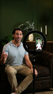 Man recording video content with a smartphone and ring light in his home studio