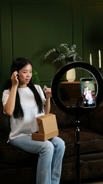 Young woman creating content for social media, applying beauty product on her face