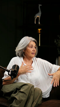 Mature woman with gray hair speaking into a microphone during a podcast interview