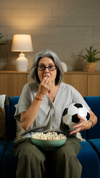 Senior woman enjoying entertainment, watching a sports game at home