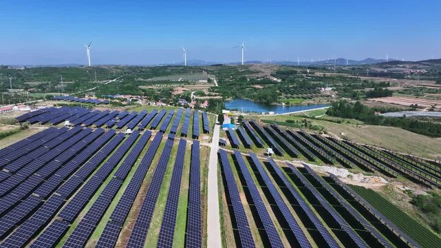 Large scale solar photovoltaic power station with wind turbines in rural landscape