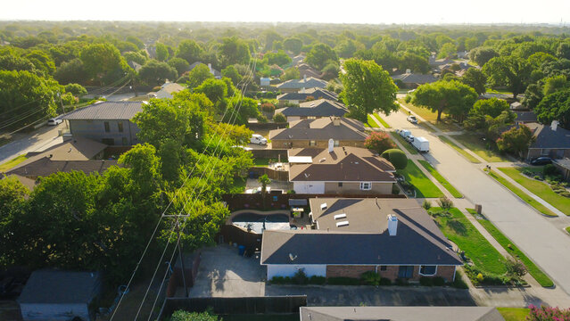 Stretched utility cables traverse residential backyards along Mobley Way within Dallas suburbs. Custom plunge pools, paved driveways accentuate classic neighborhood living, Coppell, Texas