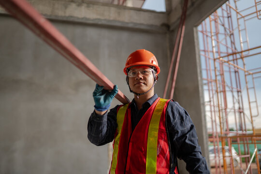 Construction Worker Carrying Steel Beam Inside Unfinished Building
