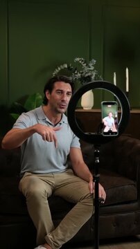 Male influencer speaking to the camera while recording a video for social media from his home