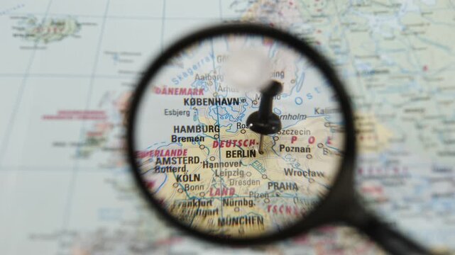 Highlighting Berlin on a printed map with a magnifying glass
