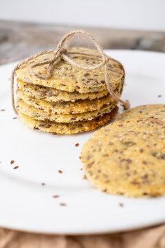 Healthy food. Grain pastry. Round crackers stack tied with jute placed on white ceramic plate. Tasty cookies with flax pumpkin seeds.