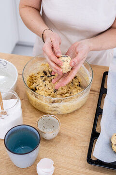 Home food. Cookies making. Woman chef hand shaping peanut dough ball pieces on table with measuring cookware preparing for baking on tray.