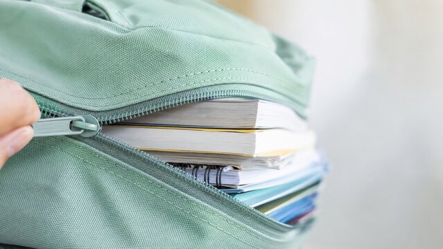 Closeup of books and notebooks inside a zippered backpack, back to school