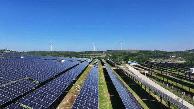 Large scale photovoltaic power station with wind turbines under clear blue sky
