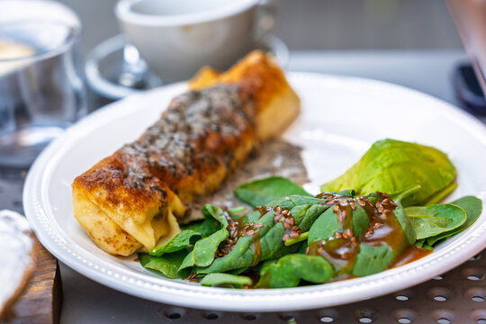Savory crepe stuffed with cheese and mushrooms served with fresh spinach salad and avocado slices