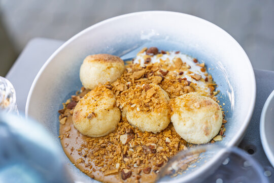 Cottage cheese pancakes with caramel sauce and crushed nuts in a ceramic bowl