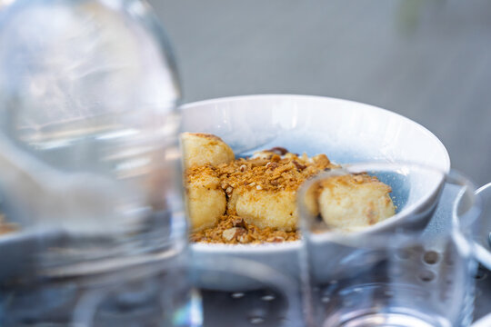 Sweet cottage cheese dumplings with toasted breadcrumbs and nuts served in a ceramic bowl