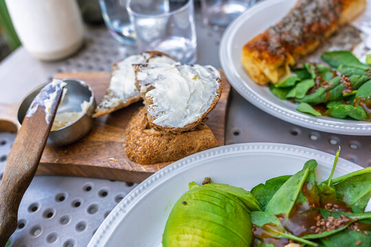 Healthy breakfast with toasted bread, butter, avocado, and fresh spinach salad on a restaurant table