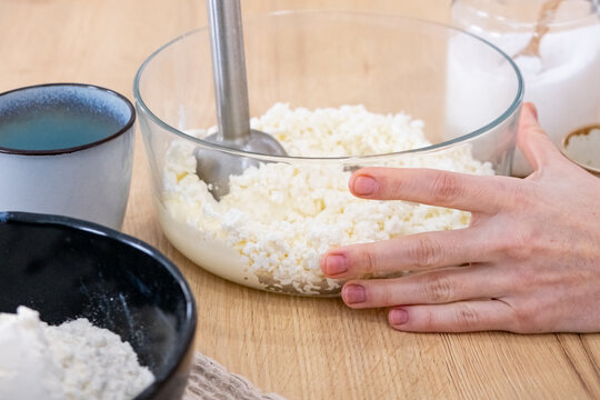 Blending food. Preparing meal. Woman chef hand mixing white cottage cheese in bowl on kitchen countertop with modern electric equipment.