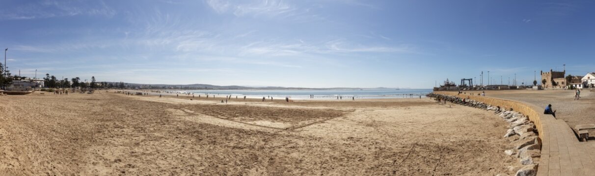 Panoramic view of a wide sandy beach next to the sea under clear skies