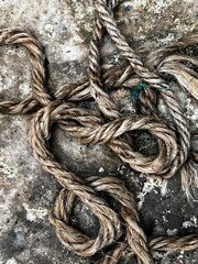 Thick natural fiber rope intertwined on weathered concrete ground during daylight with selective focus © pappu chanda