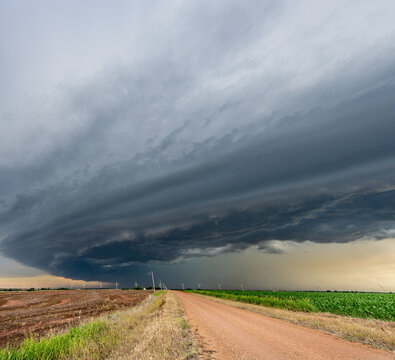 Remote dirt road framed by a storm in the Great Plains