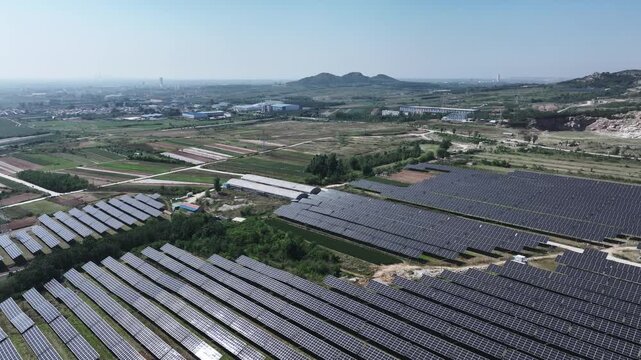 Large-scale photovoltaic power station spanning fields and rolling hills under clear blue sky