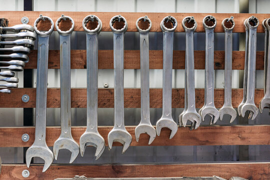 Wrench set and mechanic tools organized on wooden workshop wall for repair and maintenance.