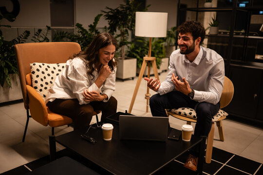 Business colleagues collaborating on laptop in modern office lounge
