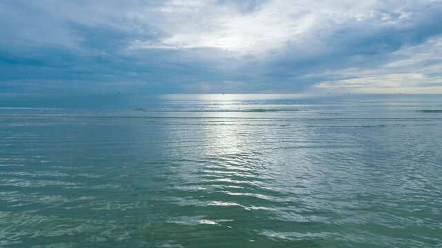 Calm turquoise sea with sunlight reflection and dramatic clouds