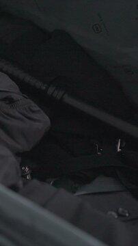 Close up of handcuffs and keys inside partially open bag. Person leg in pants appears briefly showing elastic waistband. Scene remains dimly lit throughout focusing