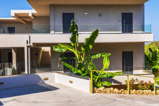 Beautiful view of modern resort building with glass balconies and banana plants. Crete. Greece.