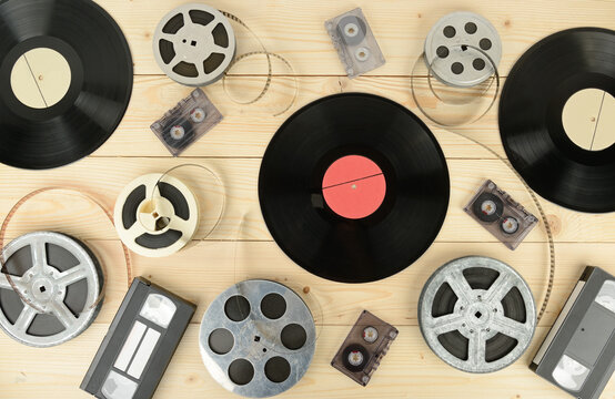 Vintage Media Collection with Vinyl Records, Audio Cassettes, VHS Tapes, and Film Reels on Wooden Background