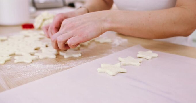 Baking cookies. Pastry preparation. Chef woman hand placing star shape flour dough on white parchment paper sheet at kitchen table.
