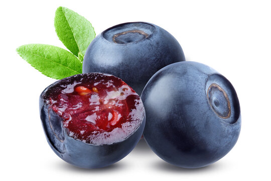 Cut bilberry showing red flesh in front of two whole berries with green leaves isolated on transparent background.
