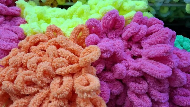 Many colorful loop yarn skeins lie stacked together in a craft store. knitting hobby, needlework supply, textile materials background.