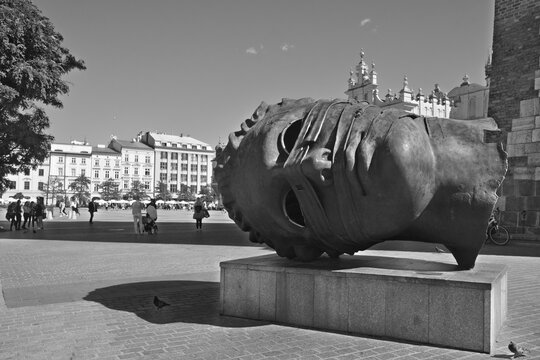 KRAKOW POLAND: Eros Bendato (Eros bound) giant head statue in Rynek Glowny, Krakow. The bronze noggin was sculpted by Igor Mitoraj in 1999 and moved to Krakow in 2003.