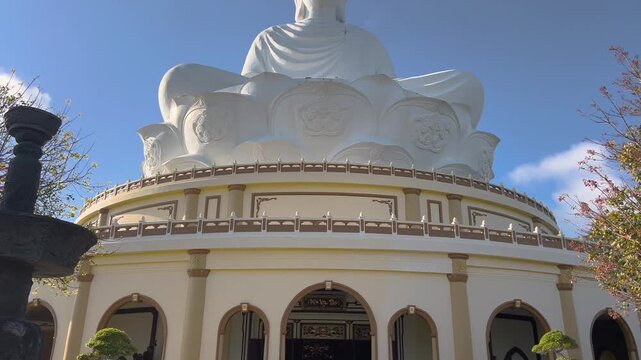 Tilt up and down shot of giant white seated Buddha statue at Ong Nui temple in Cat Tien Quy Nhon Vietnam