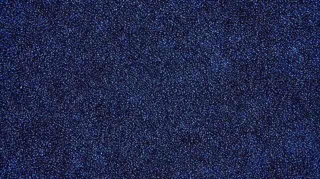 Dense blue speckled grain field with subtle tonal shifts and uniform shimmer, creating abstract moving texture across wide dark backdrop with soft contrast and depth