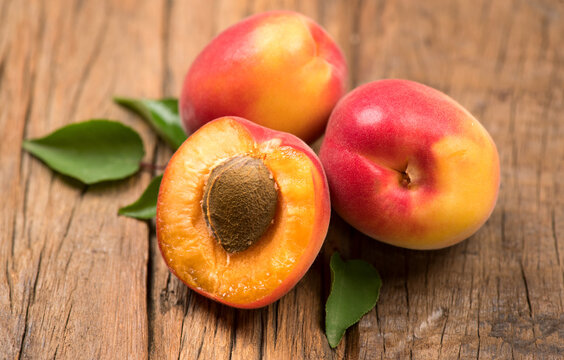 Apricots. Close-up of fresh organic apricot fruits on a rustic wooden table. Fresh bio apricot with leaves closeup, top view. 