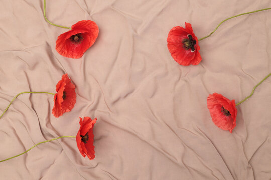 Frame, red poppy flowers on crumpled wave fabric background.