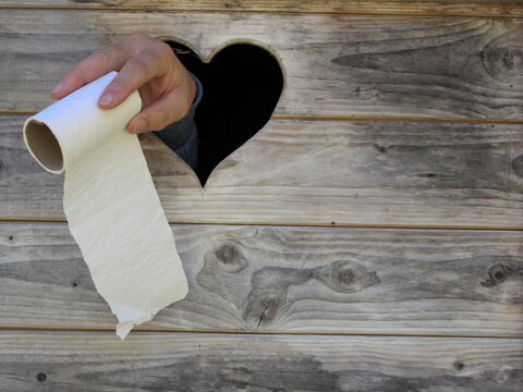 stuhlgang - defecation. hand showing toilet paper through a toilet door window. Hand zeigt Klopapier durch das Fenster einer Toilette.
