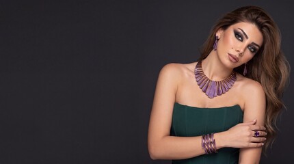Fototapeta premium Sophisticated woman wearing rose gold purple amethyst gemstone fan fringe jewelry set in green corset dress, model portrait with copy space
