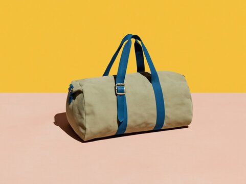 Sage green canvas duffel bag with blue straps and brass buckle, featuring a tactile woven texture for travel mockups and packing graphics