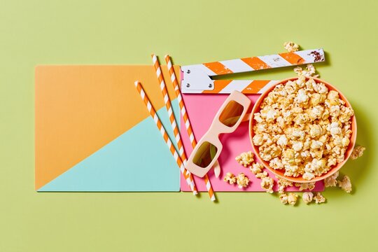Film clapperboard and bowl of buttery popcorn with glasses, a colorful and playful flat lay for movie night and streaming promotion
