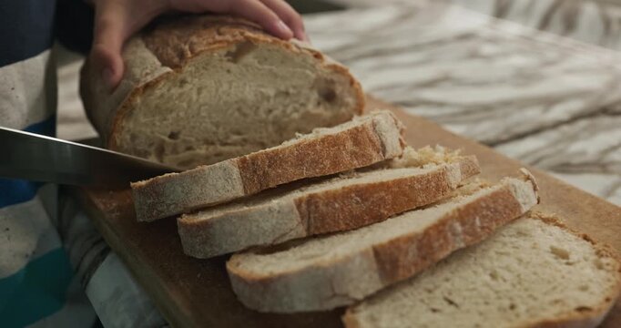 Kid hands cut bread with knife. Boy help in kitchen. 4K 10-bit