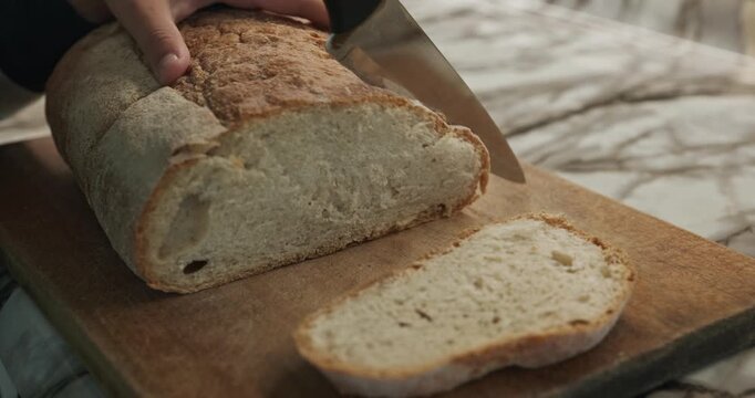Kid hands cut bread with knife. Boy help in kitchen. 4K 10-bit