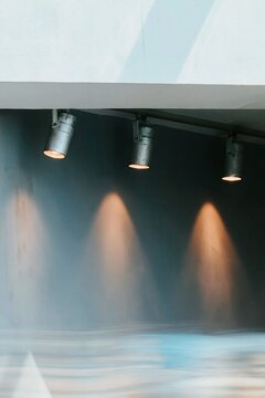 Row of gallery track lights with warm directional glows on a clean museum wall, featuring a matte finish and copy space for interior design mockups
