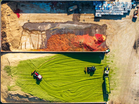 Aerial view of agricultural machinery processing green fodder at a food factory, with large piles of organic material and storage containers in Pomposa, Emilia-Romagna, Italy.