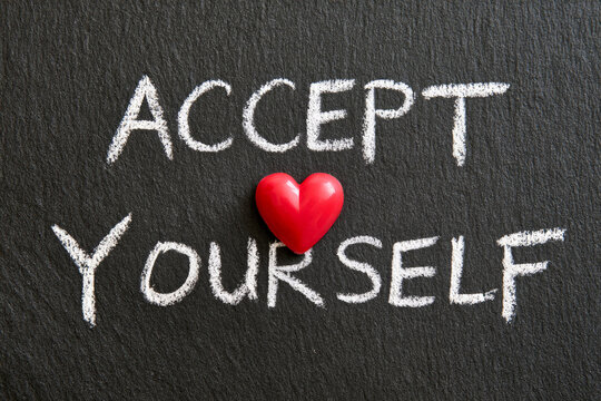 Accept yourself message is written in white chalk on a blackboard with a red heart. Self acceptance, emotional wellness, positive affirmation.